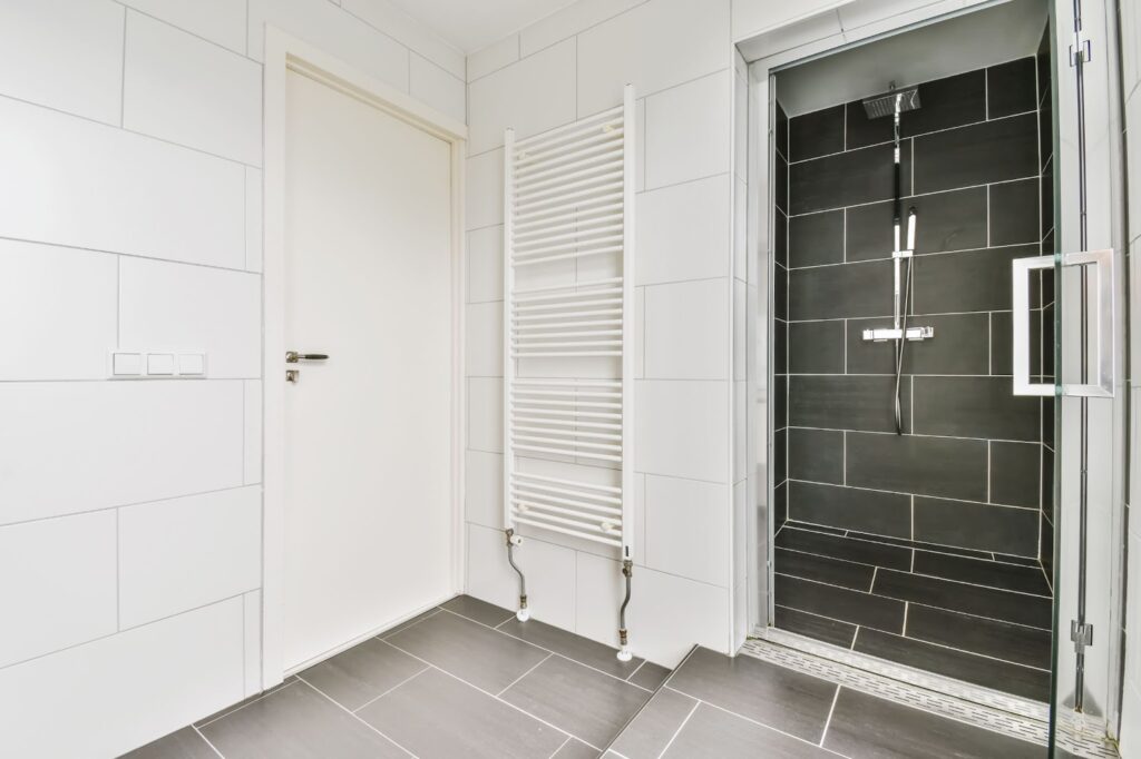 A walk-in shower with black tiles.